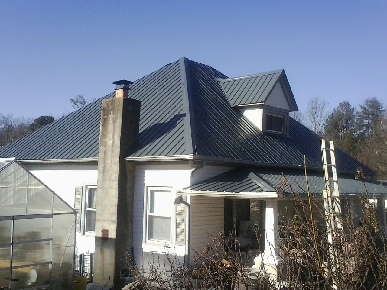 Dark blue standing seam metal roof on a white farmhouse with dormer — Slate & Tile Roof Repair by Roofing Brothers in Prescott