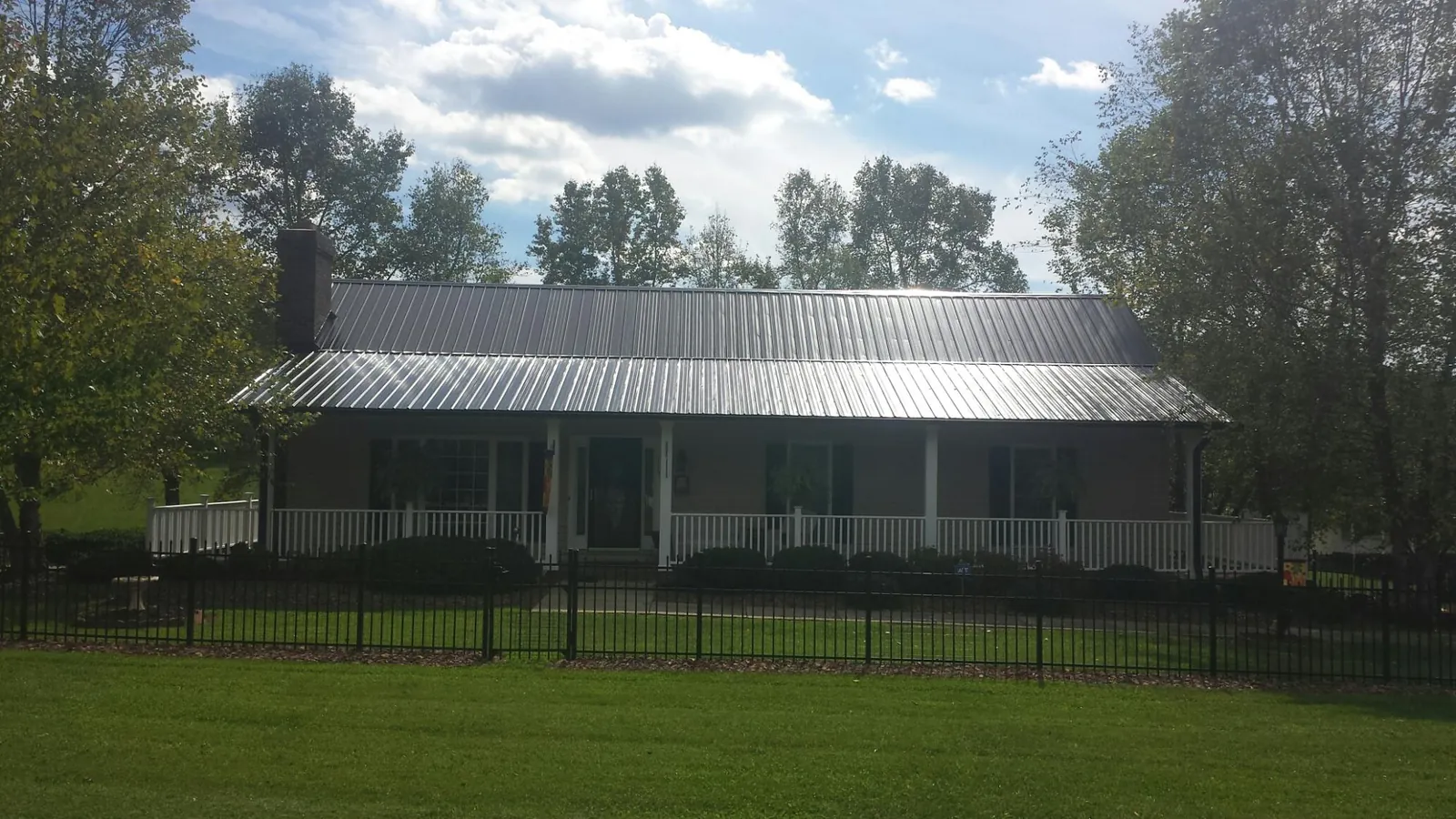 Gray metal roof on a brick ranch with a full width front porch — Gutter Guard Installation work by our crew in Prescott